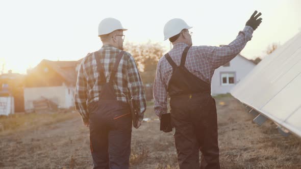 Two Factory Engineers Walking and Analyzing Construction of Solar Batteries alt