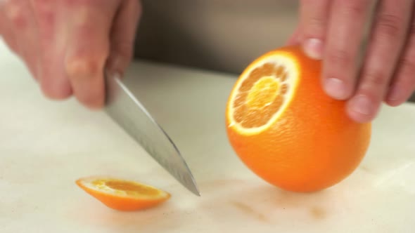 Hands with Knife Peeling Orange. alt