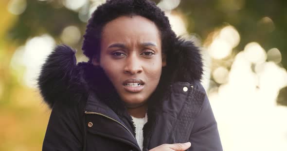 Portrait of Frozen African American Young Woman Wears Warm Jacket Stands Alone Isolated Outdoors alt