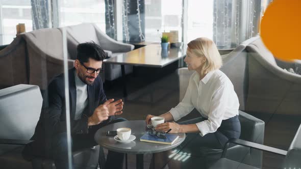 Business Partners Man and Woman Sharing News Talking in Cafe Over Coffee alt