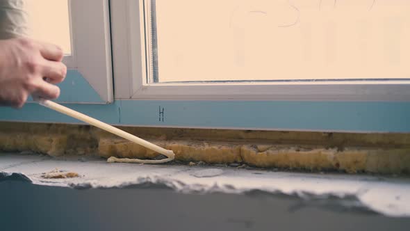 Builder Applies Spray Foam Insulation on Windowsill Closeup alt