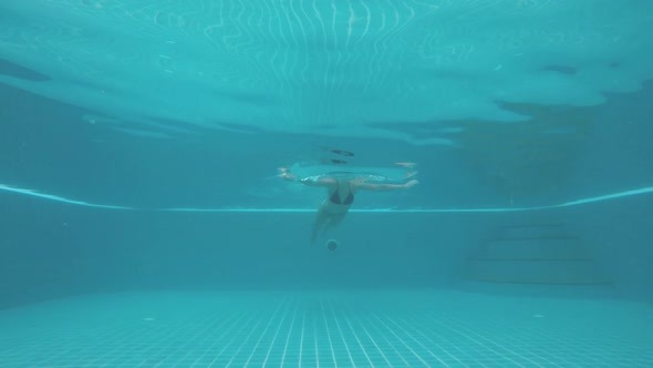 Underwater Shot of Woman's Body Swimming Towards the Camera in the Pool alt