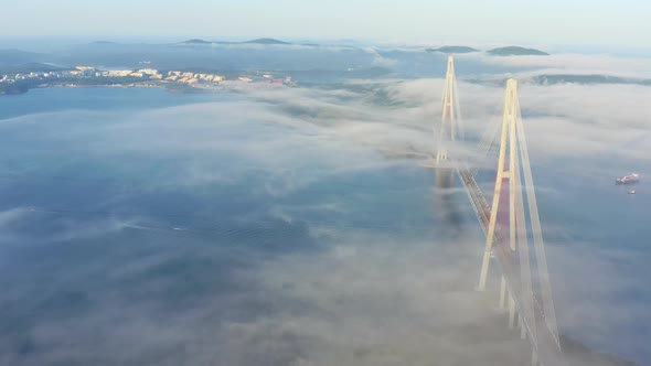 The Pylons of the Giant Cablestayed Bridge Rise Above the Seaside Morning Fog alt