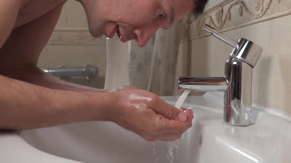 Man Washes His Face with Running Water and Soap