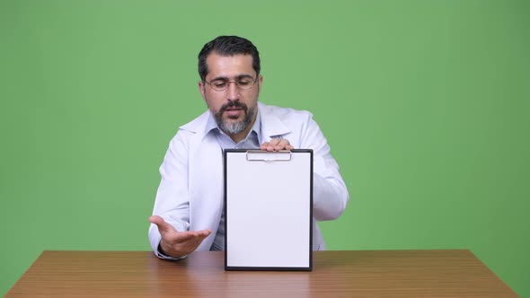 Handsome Persian Bearded Man Doctor Talking While Showing Clipboard