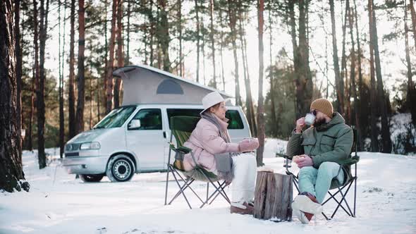 Couple of Travellers Resting in the Woods on Sunny Winter Day Enjoying Van Life