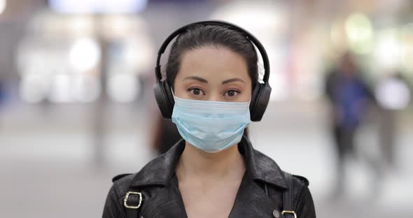 Chinese woman at train station in London wearing face mask to protect from sm alt