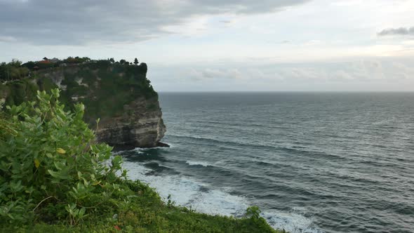 Green Uluwatu Temple Cliff and Indian Ocean Waves Hitting the Shore at Windy Sunset Bali   Wide Shot alt