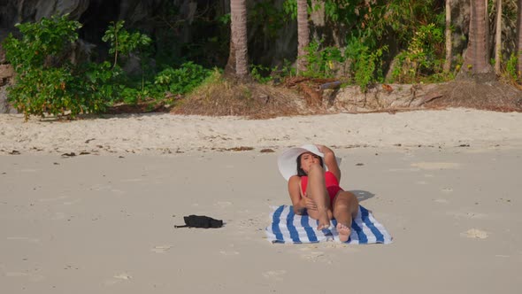 Woman In Swimsuit And Sunhat Sunbathing On Beach alt