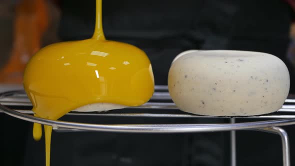 Dolly Shot Closeup Pastry Chef Pour Yellow Mirror Icing Over the Mousse Cakes and Drips Into the