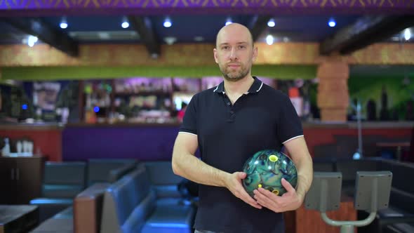 Bowling player looking in front of him while holding a ball to play alt