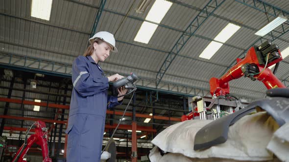 A female engineer operating a mechanical arm, she is inspecting and testing the operation of the mac