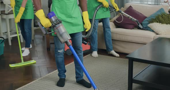 Multiracial Cleaning Team Doing wet Cleaning with Vacuums and Mop in Customer House alt