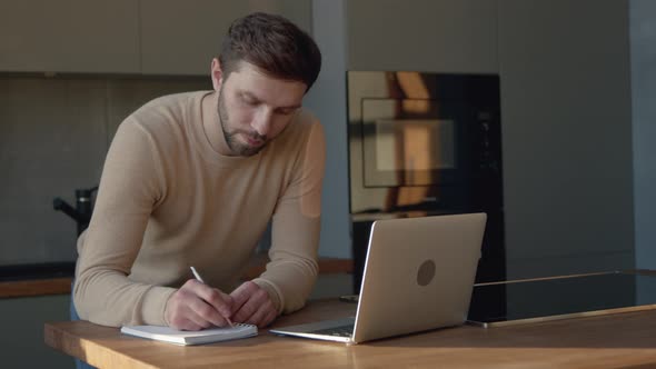Serious young man communicating by video live using computer alt