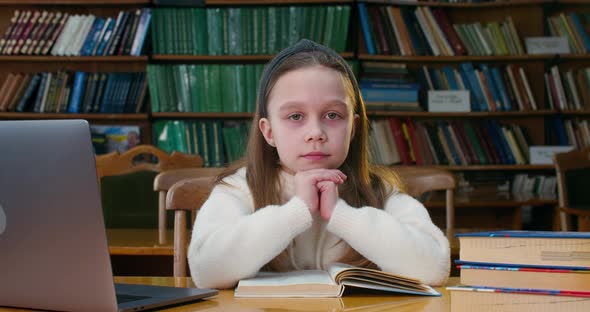 A Little Girl Is Folding Her Hands and Looking at the Camera.  alt