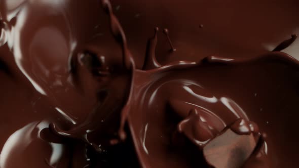 Super Slow Motion Shot of Raw Chocolate Chunks Falling Into Melted Chocolate at 1000Fps. alt