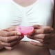 Woman In White Top Folds Reusable Silicone Menstrual Cup On Woman's Hand. Concept Of Women's Hygiene