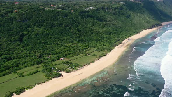 empty white sand coastline of Nyang Nyang beach in Uluwatu Bali with ocean waves crashing, aerial alt