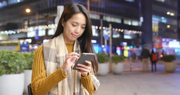 Woman working on cellphone in the city at night alt