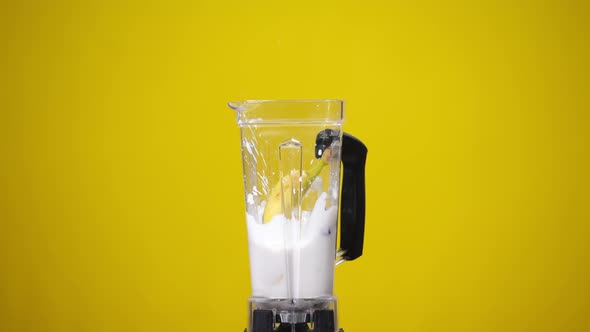 Milkshake with Strawberries at Yellow Background and Whole Banana Falling Inside Splashing Cocktail alt