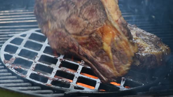 Large Juicy Beef Rib Eye Steak on a Hot Grill with Charcoal and Flames