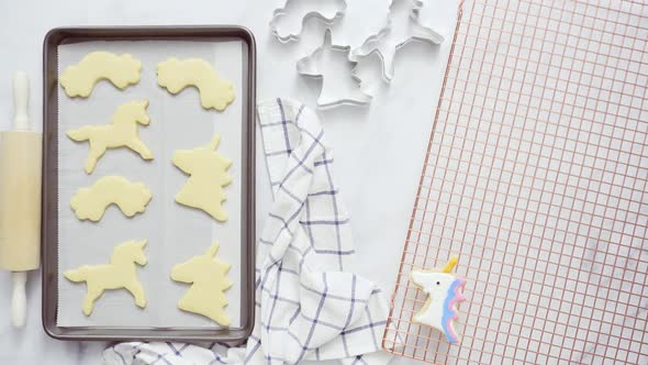Unicorn cookies decorated with royal icing drying on drying rack. alt
