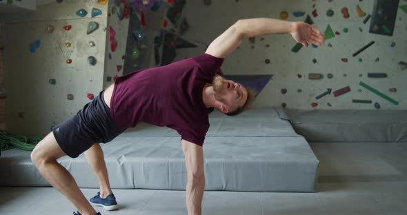 Young Bearded Athlete Warming Up Before Training on a Climbing Wall alt