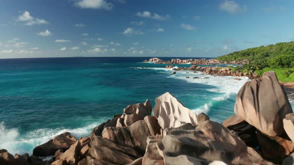 Aerial dolly pull back over an oasis of jagged pink granite boulders alt