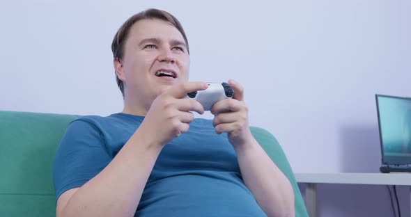 Mature Plump Man Plays Sitting on Sofa and Using Controller alt