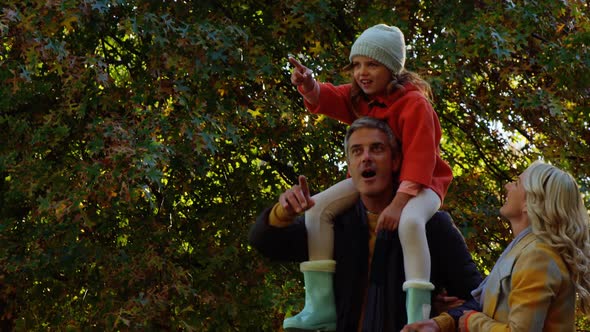 Girl on dads back with mom walking outdoors alt