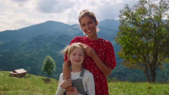 Mother Stroking Girl Head Standing in Front Mountains Closeup alt