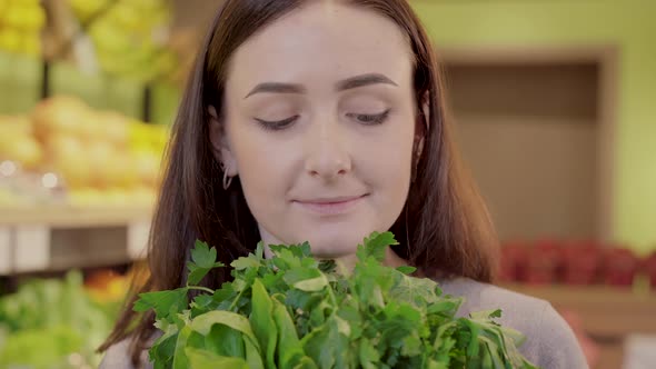 Close-up Face of Pretty Young Woman Holding Bunch of Parsley and Looking at Camera. Portrait of alt