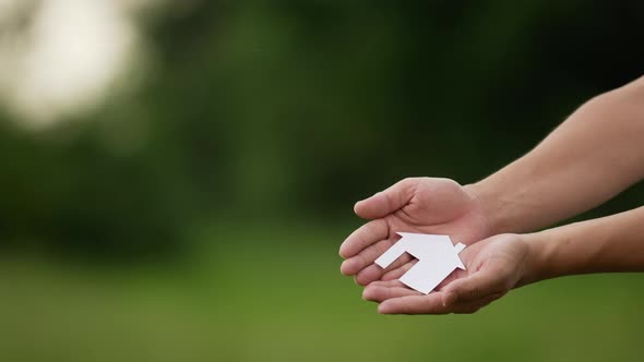 People cupped hands showing paper house alt