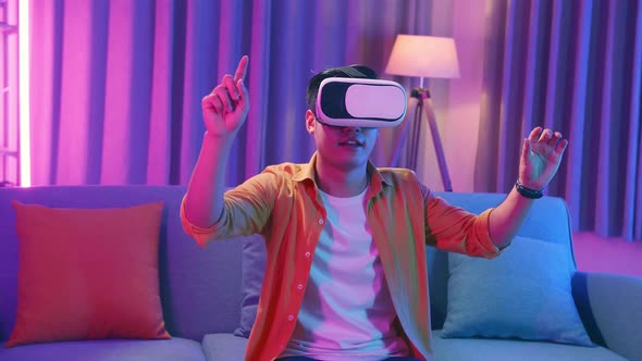 Young Asian Man Wearing Vr Headset At Living Room, Using Hand Touching And Slide alt
