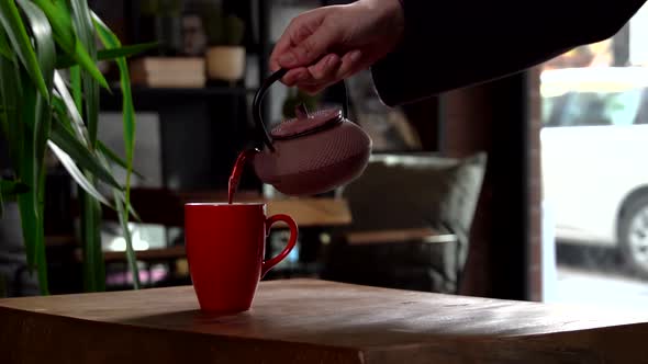 Cinematic Slow Motion Pouring Herbal Tea in Red Mug from Pink Tea Pot