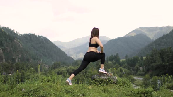 Young Sporty Woman Is Doing Lunges and Stretching Legs in Mountains, Yoga Poses.
