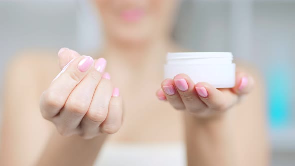 Closeup of Female Hands Holding Jag with White Skin Care Cosmetics Cream alt