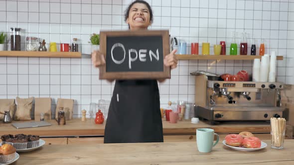 Happy Coffee Shop Worker Holding Balckboard with Sign "open" on It