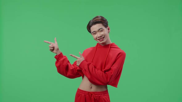The Inspired Asian Transgender Male Smile And Pointing To The Side While Standing On Green Screen alt