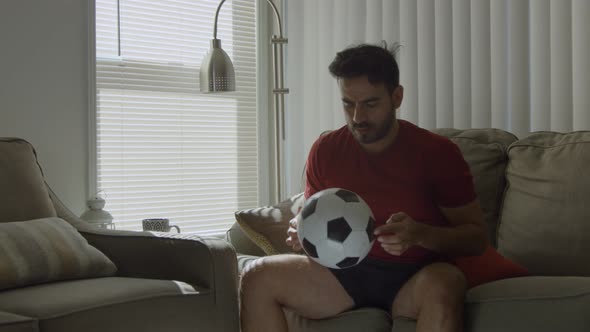 Slow Motion of Man Playing with Soccer Ball at Home Gets Up and Leaves alt
