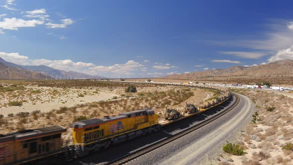 Aerial view of train carrying hundreds of US military vehicles, tanks and humvees are transported by alt