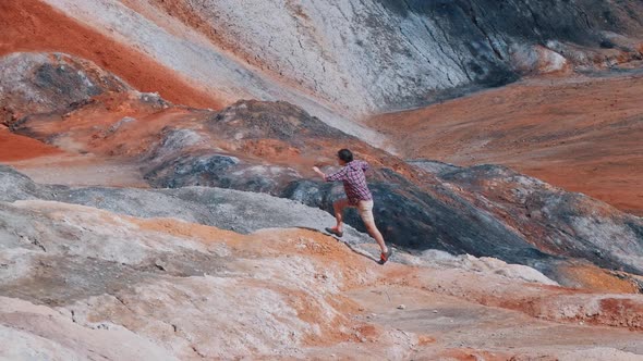 Young Man Walking on an Orange Mountains alt