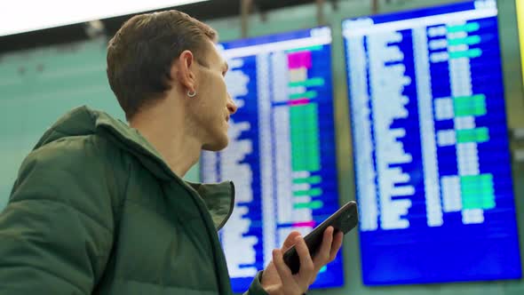 Young Man Looking at Flight Schedule at Airport