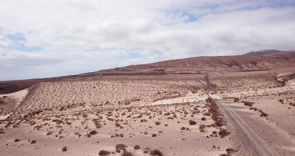 Path road in the middle of a mountains sand desert with blue bright sky in background. Arid climate alt