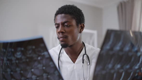 Front View Portrait African American Male Doctor Analyzing Xrays Indoors in Hospital alt