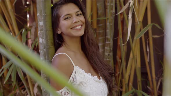 Pretty Smiling Woman Leaning on Bamboo Tree alt