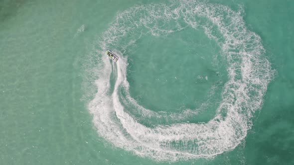 Aerial top view of jet ski or boat drawing a shape on sea ocean turquoise water. Adventure alt