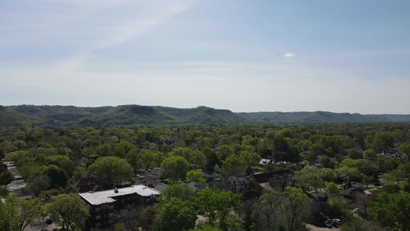 Lush tree-filled community in valley with mountains in background. Blue sky with streaks of clouds.