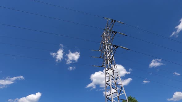 High voltage power line against a blue sky with moving clouds. Timelapse.