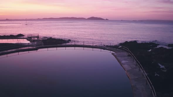Guernsey tidal bathing pools with Herm Island behind at sunrise, Channel Islands, UK. Aerial drone v alt